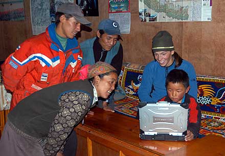 Mom and friends looking at Lhakpa working very concentrated on the computer