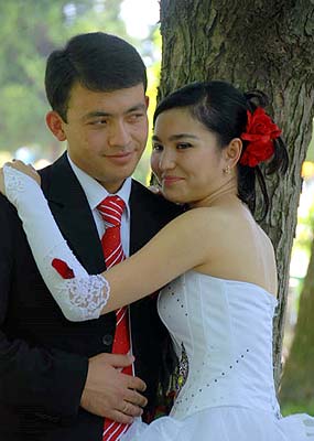 Newly married Uzbekistan couple posing for pictures in the park on a Sunday afternoon.