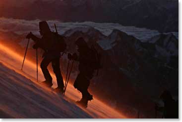 A couple of climbers show the steepness of the slop to the summit in the early dawn 
