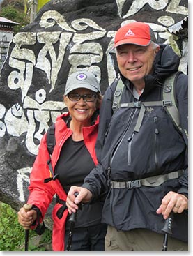 Sharon and Jim stand before a carved and painted Mani rock, with the repetitive inscription “Om Mani Padme Om”